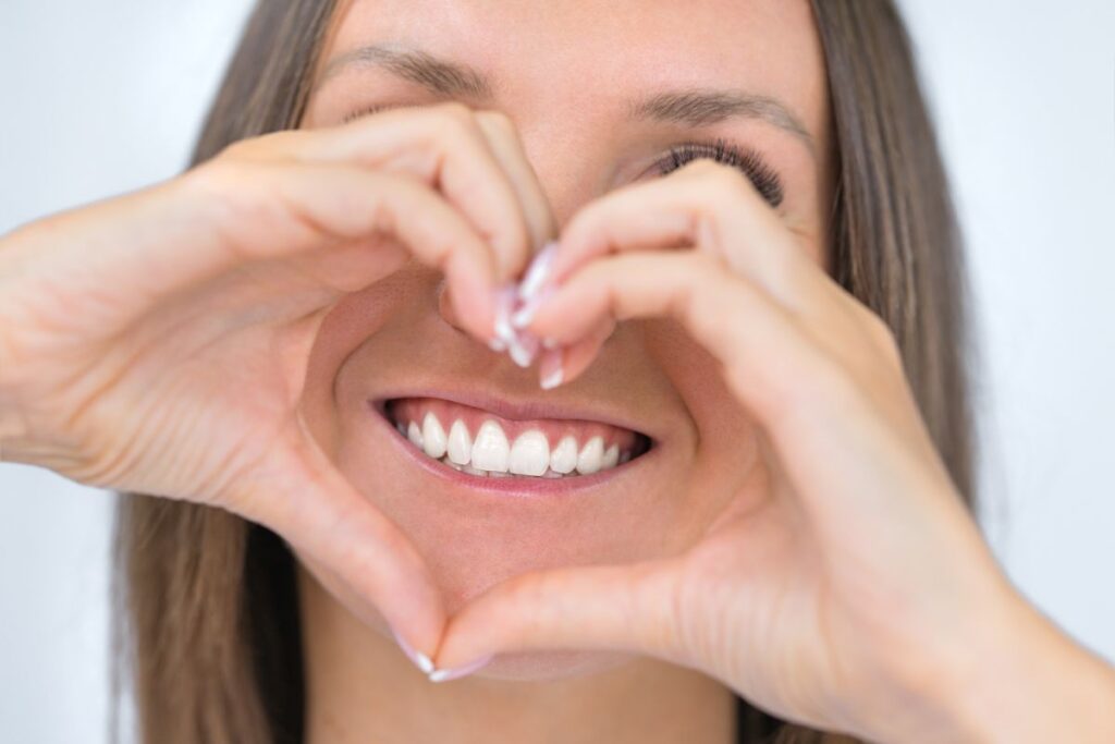 Mujer realizando el símbolo de corazón con las manos alrededor de su boca - Clínica Mayor 4